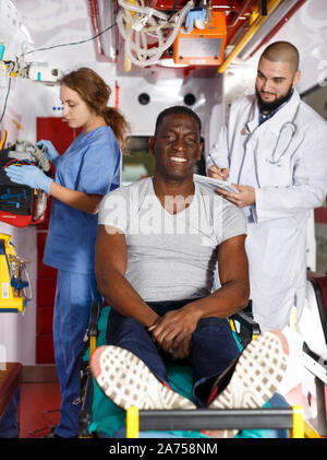 Portrait von fröhlichen afro Patient mit zwei Sanitäter im Krankenwagen Auto Stockfoto