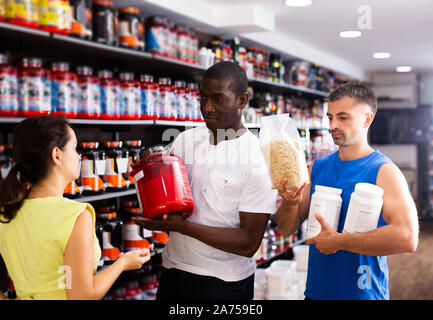 Junge körperlich fit Menschen diskutieren moderne Sport Ernährung Produkte im Shop Stockfoto