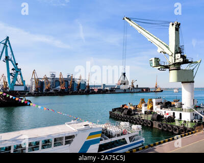 Floating Lastkran mit einer Kelle in der Hafenstadt über das Meer und Getreidespeicher Aufzüge, Tugboat unterstützen, Boote und Kräne. Industrielle Landschaft des Meeres c Stockfoto