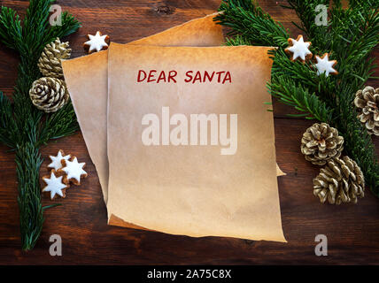 Papier mit Text Liebes Christkind, zwischen Tannenzweigen, Zimt Sterne und Tannenzapfen auf rustikalen dunklen Holz, Weihnachten Wunschliste oder Brief an Santa Clau Stockfoto