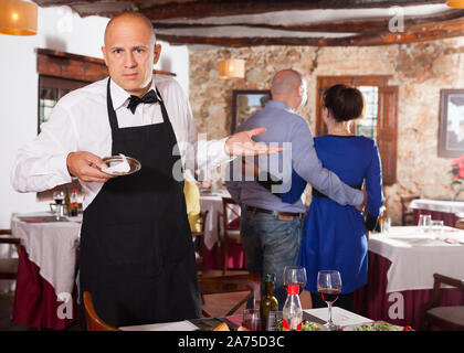 Männliche Kellner demonstriert seine umgekippt mit kleinen Tipps vom Restaurant Besucher Stockfoto