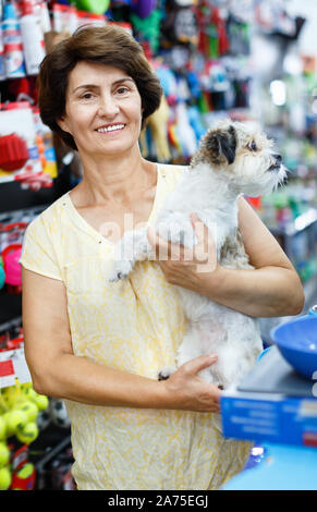Portrait von glücklich, froh, heiter ältere Frau besuchen Pet Supplies Store mit ihren niedlichen Welpen von havaneser Stockfoto