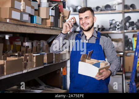 Attraktiven männlichen Arbeitnehmers Sortierung Sanitärtechnik Details in der Werkstatt Stockfoto