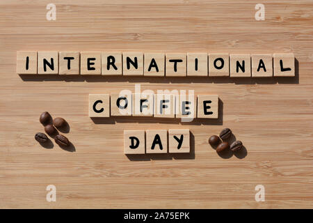 Internationaler Tag des Kaffees. In 3d Holz- Buchstaben des Alphabets mit Kaffeebohnen Wort auf einer Bambus Holz Hintergrund Stockfoto