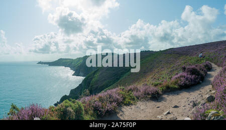 Plevenon, Bretagne/Frankreich - 20 Augsut 2019: Familie Wandern auf einem Weg durch violette Heide Wiesen an der Atlantikküste Stockfoto