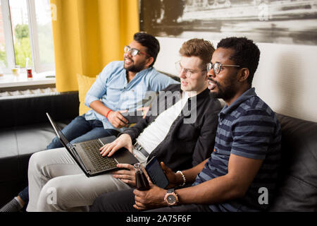 Gruppe von Multiethnischen männliche Freunde gerade online Sport Spiel mit Laptop auf dem Sofa zu Hause sitzen, Warten auf Sieg nach Wetten in Online bookmak Stockfoto