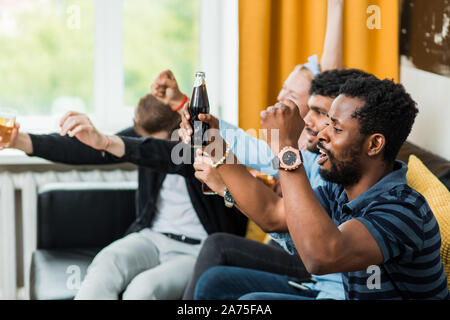 Ziel ist. Sehr aufgeregt, multi-ethnische Freunde oder Fußball-Fans Spaß durch Sport übereinstimmen, jubeln und schreien und Trinken einige Getränke sittin Stockfoto