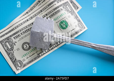 Ein Dollar Rechnungen durch einen Hammer aus rohem Fleisch auf einem blauen Hintergrund zu schlagen zerquetscht. Die amerikanische Währung. Das Konzept der Verteuerung der Produkte. Stockfoto