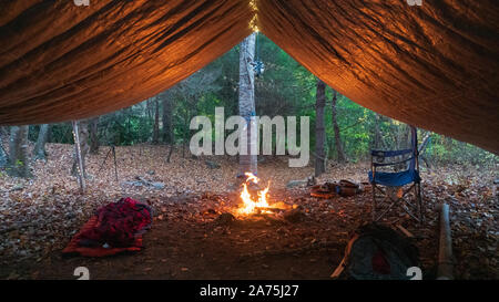 Primitive Tarp Tierheim mit Lagerfeuer und Lichterketten. Survival Bushcraft Setup in den Blue Ridge Mountains in der Nähe von Asheville. Stockfoto