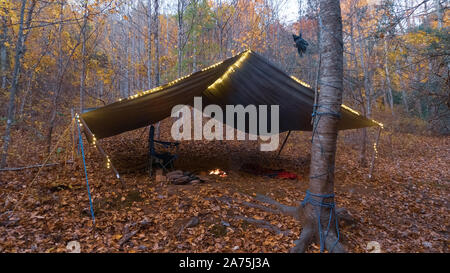 Primitive Tarp Tierheim mit Lagerfeuer und Lichterketten. Survival Bushcraft Setup in den Blue Ridge Mountains in der Nähe von Asheville. Stockfoto