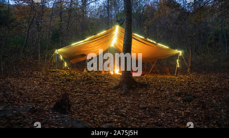 Primitive Tarp Tierheim mit Lagerfeuer und Lichterketten. Survival Bushcraft Setup in den Blue Ridge Mountains in der Nähe von Asheville. Stockfoto
