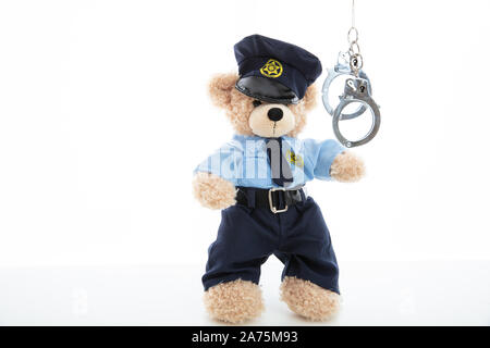 Polizei und Verhaftung Konzept. Niedlichen Teddybären in Polizeioffizier einheitliche und Handschellen vor weißem Hintergrund Stockfoto