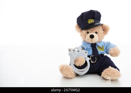 Polizei und Verhaftung Konzept. Niedlichen Teddybären in Polizeioffizier einheitliche und Handschellen vor weißem Hintergrund Stockfoto