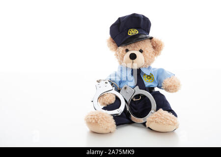 Polizei und Verhaftung Konzept. Niedlichen Teddybären in Polizeioffizier einheitliche und Handschellen vor weißem Hintergrund Stockfoto