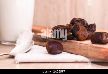 Getrocknete Datteln, Milch auf Stoff Hintergrund. Konzept. Termine Holzbrett. Vegetarisches Essen. Kopieren Sie Platz. Closeup Hintergrund Stockfoto