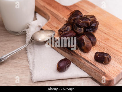 Getrocknete Datteln, Milch auf Stoff Hintergrund. Konzept. Termine Holzbrett. Vegetarisches Essen. Kopieren Sie Platz. Closeup Hintergrund Stockfoto