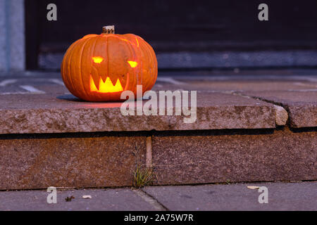 Lächelnd und glänzende Halloween Kürbis in der Dunkelheit auf dem Boden liegen. In Deutschland, in Bayern, im Oktober. Stockfoto