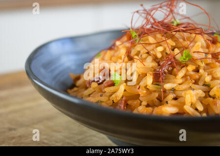 Essen Fotografie eines schwarzen Keramik Schüssel mit rotem Reis und roter Pfeffer Threads. Stockfoto