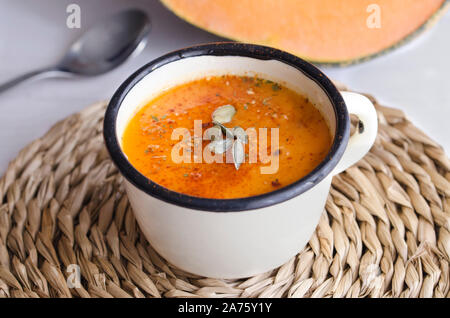 Selbstgemachte Kürbissuppe mit Spice in metallischen Becher mit frischen Toast auf hölzernen Tisch. Traditionelle Herbst essen für gesunden Lebensstil Stockfoto