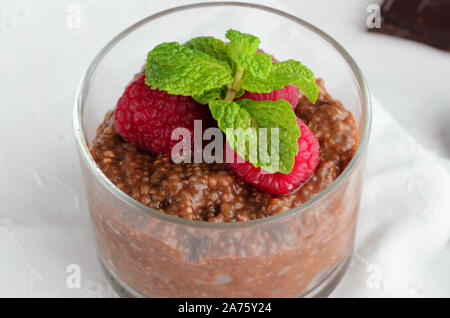 Raw vegan Dessert, Chia Schokoladenpudding mit Mandelmilch und Himbeeren in Glas auf Holz- Tabelle. Gesunde Ernährung Konzept. Stockfoto