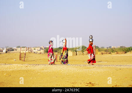 Jaisalmer, Indien - 27. Februar 2018: Indische Damen mit einem Eimer Wasser in der Nähe der Wüste Thar. Stockfoto