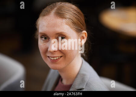 Porträt der rothaarige Junge Geschäftsfrau, Lächeln auf die Kamera beim Sitzen im Cafe Stockfoto