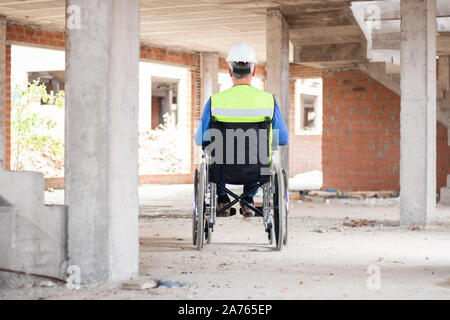 Rearvision eines Rollstuhls bau Techniker die Überwachung einer Baustelle mit Helm und Warnweste arbeiten. Behinderung Konzept Stockfoto