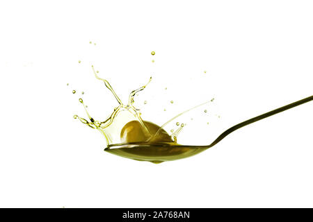 Tröpfchen, die aus einer Olive, die auf einen Löffel voll von Olivenöl fällt Stockfoto