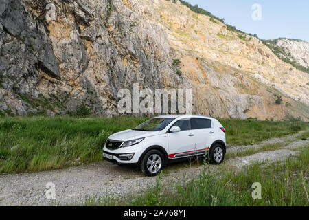 Auto Kia Sportage awd oder 4x4, Farbe weiß, auf einem Weg, der an der Spitze eines felsigen Berg führt geparkt, mit einem sehr steilen Felsen im Hintergrund Stockfoto