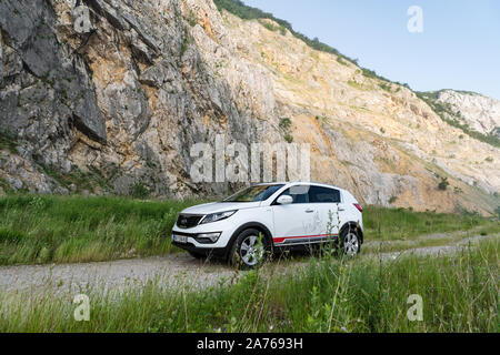 Auto Kia Sportage awd oder 4x4, Farbe weiß, auf einem Weg, der an der Spitze eines felsigen Berg führt geparkt, mit einem sehr steilen Felsen im Hintergrund Stockfoto