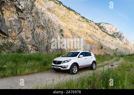 Auto Kia Sportage awd oder 4x4, Farbe weiß, auf einem Weg, der an der Spitze eines felsigen Berg führt geparkt, mit einem sehr steilen Felsen im Hintergrund Stockfoto