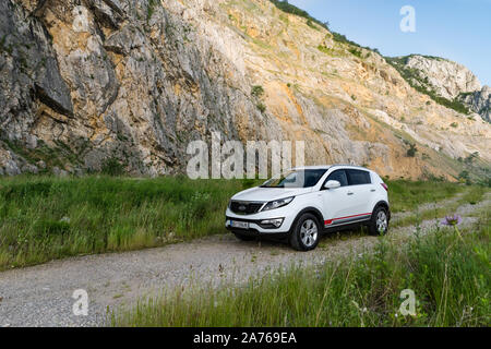 Auto Kia Sportage awd oder 4x4, Farbe weiß, auf einem Weg, der an der Spitze eines felsigen Berg führt geparkt, mit einem sehr steilen Felsen im Hintergrund Stockfoto