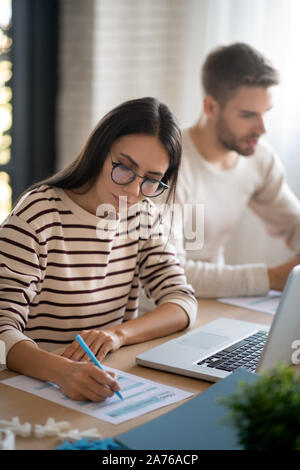 Frau Brille füllen die Steuererklärung in der Nähe von Ehemann sitzen Stockfoto