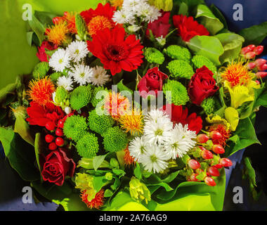 Blumenstrauß im französischen Stil (Paris). Chrysanthemen, Rosen, Lilien und anderen Blumen in Orange, Rot, Grün und Weiß. Stockfoto