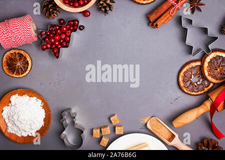 Weihnachtsbäckerei. Zutaten für die Herstellung von Plätzchen oder Lebkuchen und Gewürzen auf graue Tabelle, Ansicht von oben. Leere Platz für Text. Stockfoto