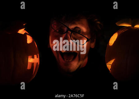 Erschrocken Mann in Gläser zwischen zwei Halloween Kürbisse. Halloween Konzept