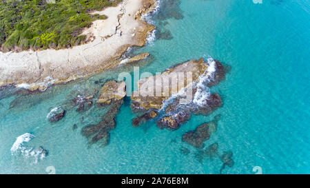 Luftaufnahme von Felsformationen im blauen Wasser der Adria, an der malerischen Küste Apuliens, in der Nähe von Baia dei Turchi, Süditalien. Stockfoto