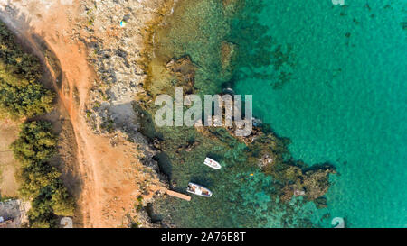 Luftaufnahme von felsigen Strand am türkisblauen Adria mit Boote in der Nähe der Ufer vertäut, Apulien Küste, Region Süd Italien. Stockfoto