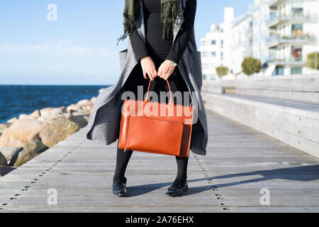 Person, die auf der Promenade mit rotem Leder Tasche Stockfoto