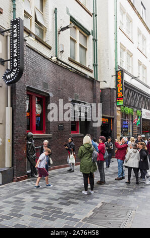 Touristen nehmen Sie Fotos mit einem John Lennon Statue außerhalb der Wall of Fame Bar und Cavern Pub auf der Mathew Street, Liverpool, Großbritannien Stockfoto