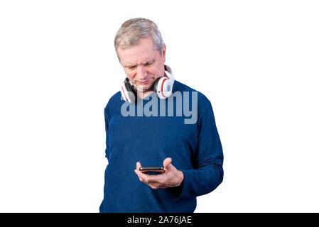 Ein älterer Mann mit einem Telefon. Mit drahtlosen Kopfhörern auf dem Hals. Auf einem weißen Hintergrund. Stockfoto