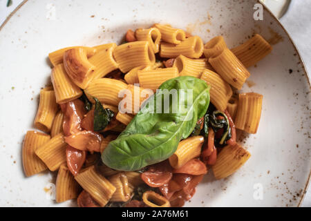 Penne Pasta italienisches Essen serviert mit Tomaten und Gemüse auf einer weißen Platte Stockfoto