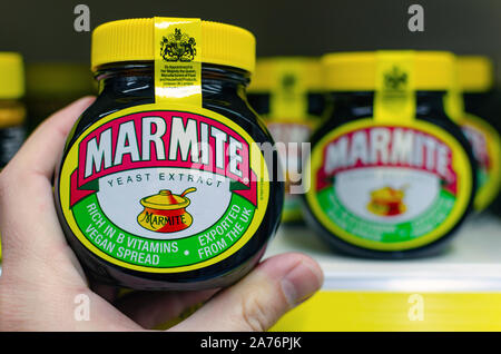 Marmite jar halten Sie in einer Hand neben dem Regal mit den anderen Gläsern. Traditionelle englische Produkt der Hefe. Stockfoto