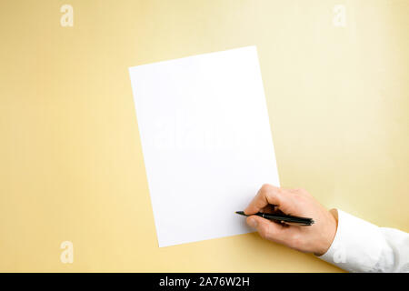 Männliche Hand mit Stift und schreiben auf leeres Blatt auf gelbem Hintergrund für Text oder Design. Leere Vorlagen für Kontakt, Werbung oder für den Einsatz in Unternehmen. Finanzen, Büro, Einkäufe. Mock up. Copyspace. Stockfoto