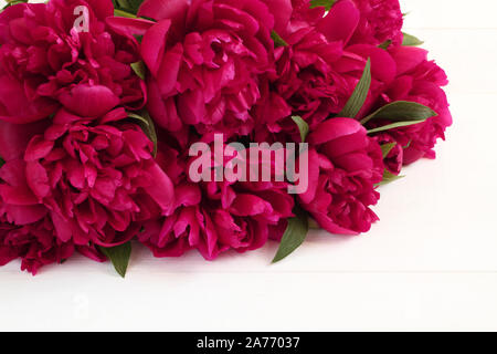 Blumenstrauß aus magenta Pfingstrosen liegen auf weiße Holztisch. Nahaufnahme Stockfoto