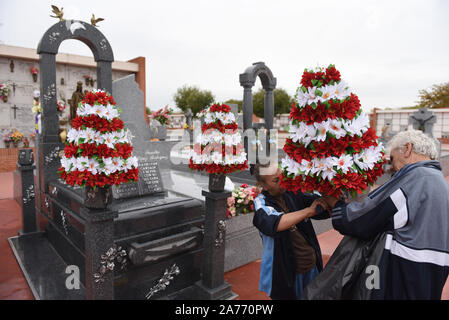 Ein paar ein Grab mit Blumen an Sur Friedhof in Madrid schmücken, vor dem 1. November feiern für Allerheiligen. Allerheiligen ist ein katholischer Feiertag, wo Menschen Friedhöfe im ganzen Land besuchen Sie Respekt zu Ihren verstorbenen Verwandten zu bezahlen. Stockfoto