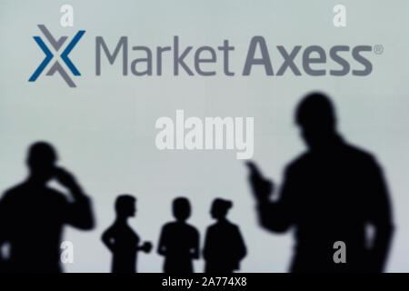 Die MarketAxss Logo ist auf einen LED-Bildschirm im Hintergrund, während eine Silhouette Person ein Smartphone verwendet (nur redaktionelle Nutzung) Stockfoto