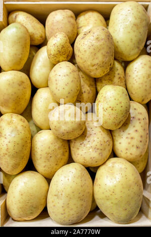 Frische Kartoffeln im Holzkasten auf Holztisch, Ansicht von oben. Stockfoto