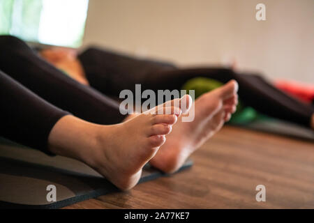 Selektive Foto von einer Gruppe von Studenten sitzen auf Yoga Matten auf dem Boden vor ihrer Lehrer, der ihnen Anweisungen Stockfoto