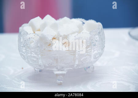 Glas Schüssel mit Zucker Würfel gefüllt. Würfelzucker in Schüssel auf weißem Hintergrund. Stockfoto
